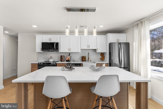 kitchen with appliances with stainless steel finishes, a center island, sink, and white cabinets