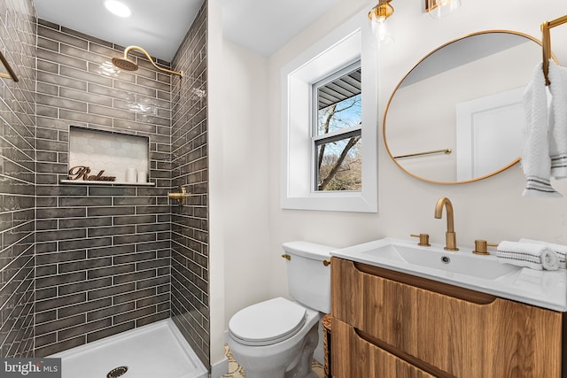 bathroom featuring tiled shower, vanity, and toilet