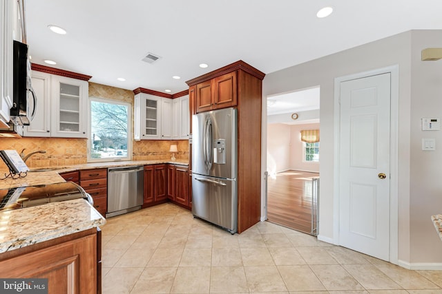 kitchen featuring sink, tasteful backsplash, light tile patterned floors, appliances with stainless steel finishes, and light stone countertops