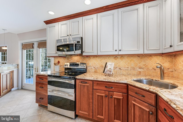 kitchen with appliances with stainless steel finishes, pendant lighting, white cabinetry, sink, and backsplash