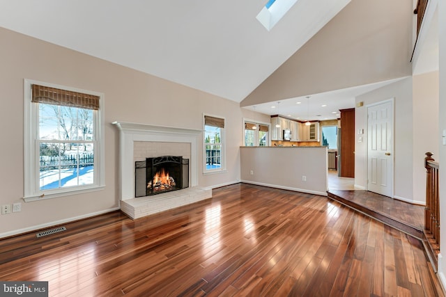 unfurnished living room with wood-type flooring, a fireplace, and a skylight