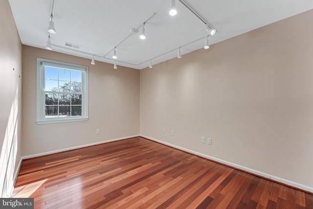 unfurnished room with hardwood / wood-style floors and rail lighting