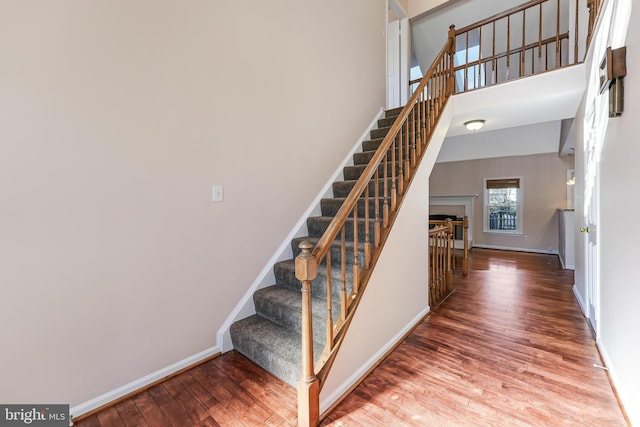 stairs featuring hardwood / wood-style flooring and a high ceiling