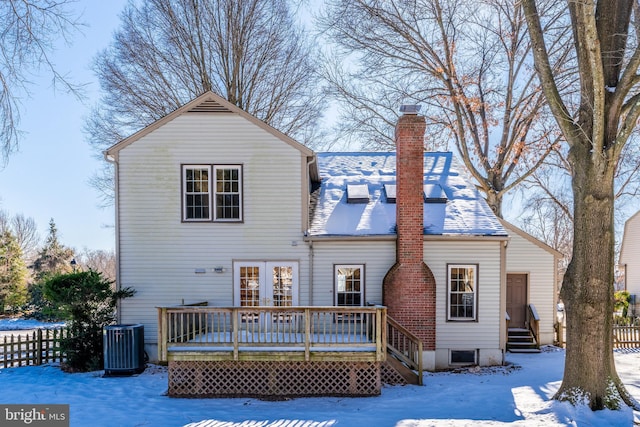 snow covered rear of property featuring a wooden deck and central AC unit