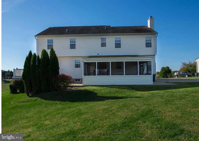 rear view of house with a sunroom and a lawn