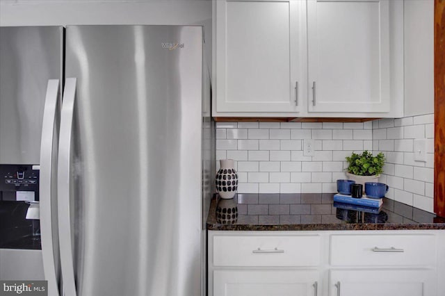 kitchen with white cabinetry, dark stone countertops, tasteful backsplash, and stainless steel fridge