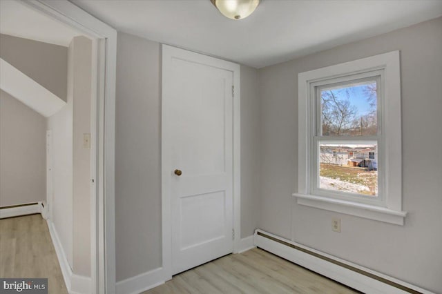 interior space with a baseboard radiator, light wood-type flooring, and a wealth of natural light