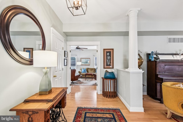 foyer entrance featuring decorative columns, ceiling fan, and light wood-type flooring