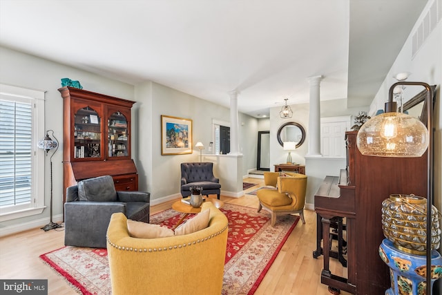 living room with ornate columns and light wood-type flooring