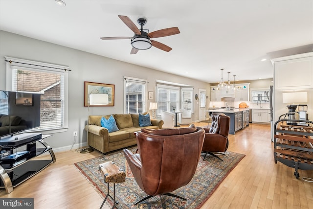 living room featuring sink, light hardwood / wood-style floors, and ceiling fan