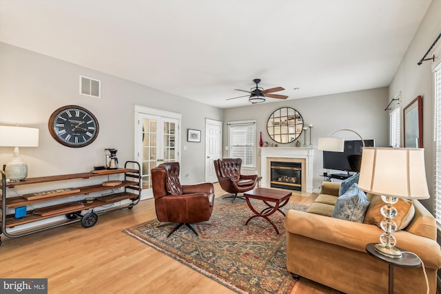 living room featuring wood-type flooring, ceiling fan, and french doors