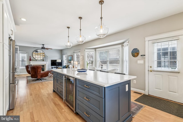 kitchen with white cabinetry, wine cooler, hanging light fixtures, ceiling fan, and light hardwood / wood-style floors