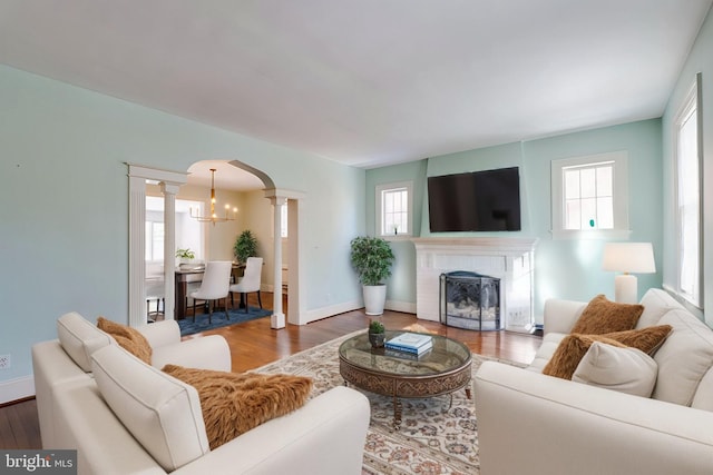 living room with a notable chandelier, decorative columns, and hardwood / wood-style flooring