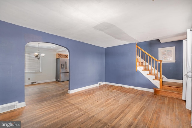 interior space with an inviting chandelier, ornamental molding, and hardwood / wood-style floors