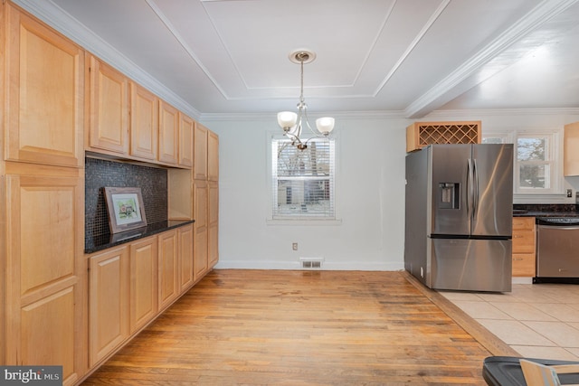 kitchen featuring decorative light fixtures, plenty of natural light, light brown cabinets, and stainless steel appliances