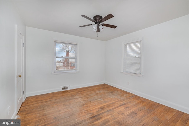 empty room with ceiling fan, a wealth of natural light, and hardwood / wood-style flooring