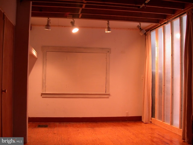 empty room with wood-type flooring and track lighting