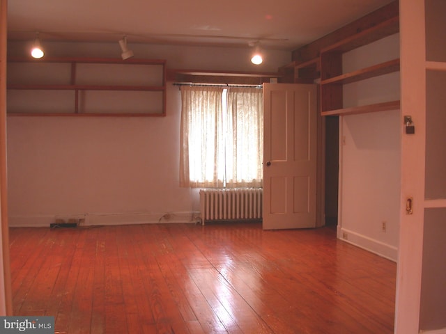 empty room featuring hardwood / wood-style flooring and radiator heating unit