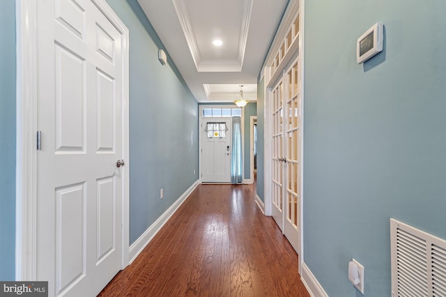 doorway to outside featuring ornamental molding, dark hardwood / wood-style floors, and a tray ceiling