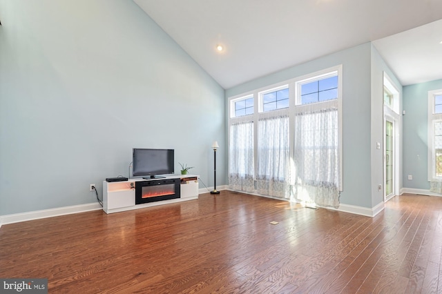 unfurnished living room featuring a high ceiling and hardwood / wood-style floors