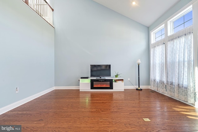 unfurnished living room featuring high vaulted ceiling and hardwood / wood-style floors