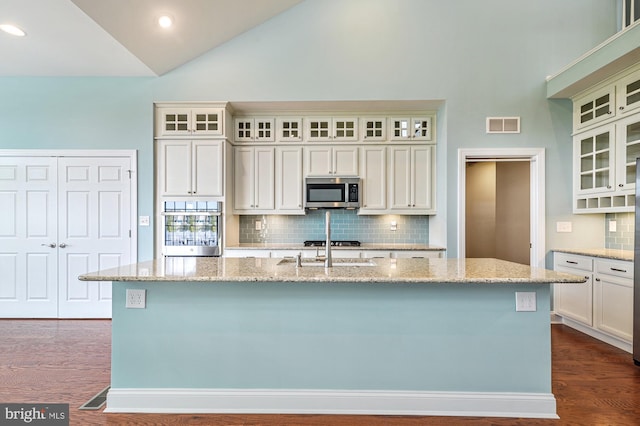 kitchen featuring appliances with stainless steel finishes, decorative backsplash, and a center island with sink