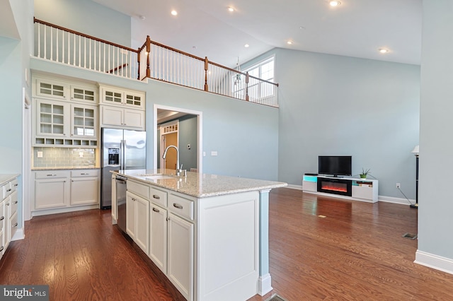 kitchen with sink, an island with sink, backsplash, high vaulted ceiling, and appliances with stainless steel finishes