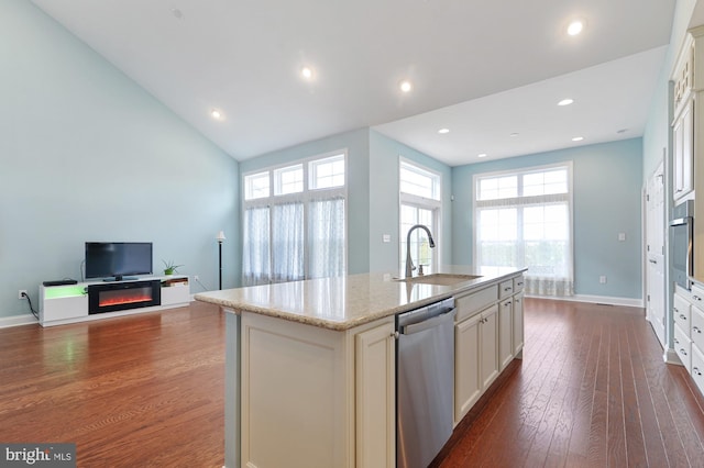 kitchen with sink, light stone counters, dark hardwood / wood-style floors, a center island with sink, and appliances with stainless steel finishes