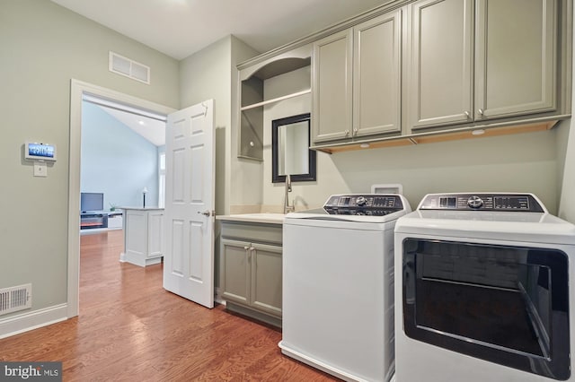 laundry room with separate washer and dryer, cabinets, sink, and wood-type flooring