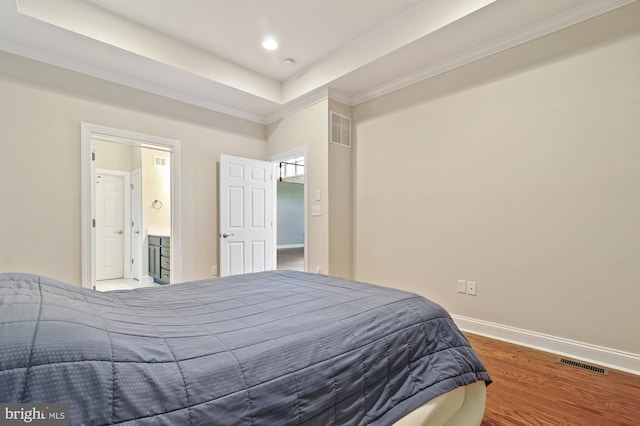 bedroom featuring hardwood / wood-style flooring, a raised ceiling, and ensuite bath