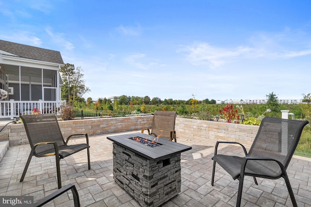 view of patio / terrace with an outdoor fire pit and a sunroom