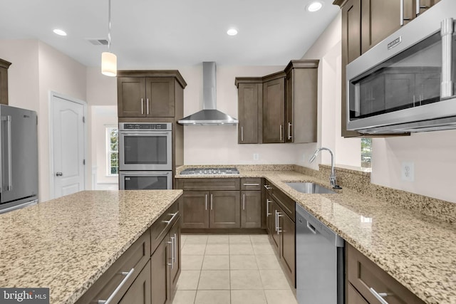 kitchen featuring wall chimney exhaust hood, dark brown cabinets, a sink, and stainless steel appliances