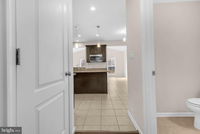 kitchen with light tile patterned floors, recessed lighting, baseboards, dark brown cabinets, and stainless steel microwave