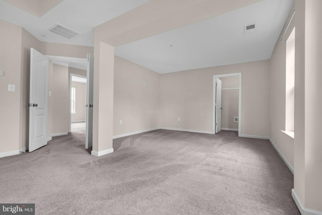 unfurnished room with carpet, visible vents, and baseboards