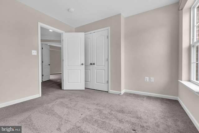 unfurnished bedroom with multiple windows, carpet, a closet, and baseboards