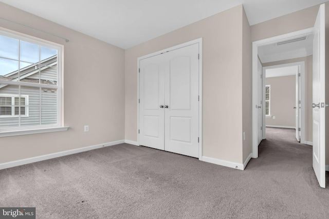 unfurnished bedroom featuring carpet floors, multiple windows, and baseboards