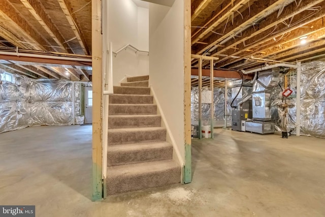 unfinished basement featuring heating unit and stairway