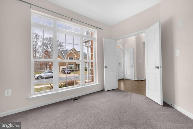 carpeted spare room featuring visible vents and baseboards