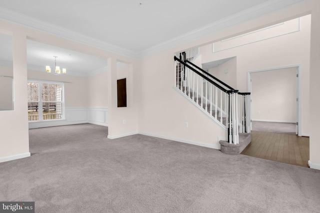 unfurnished living room with a chandelier, carpet flooring, baseboards, stairs, and crown molding