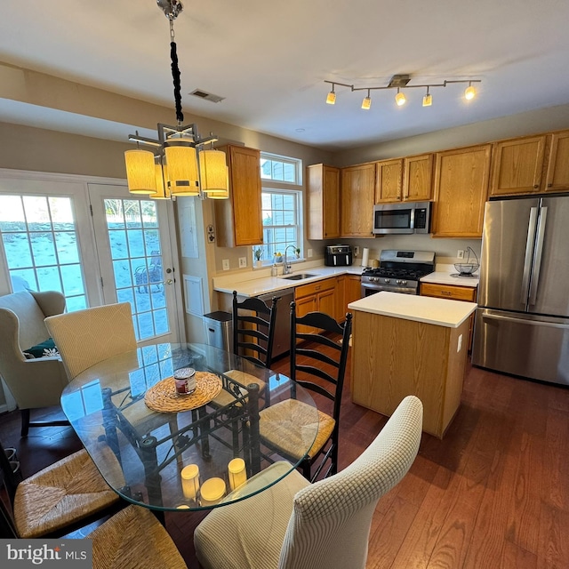 kitchen with sink, a center island, dark hardwood / wood-style flooring, pendant lighting, and appliances with stainless steel finishes