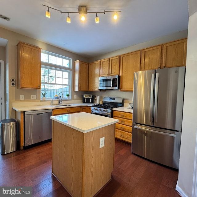 kitchen featuring appliances with stainless steel finishes, dark hardwood / wood-style flooring, a center island, and sink