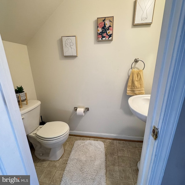 bathroom featuring toilet, vaulted ceiling, and sink