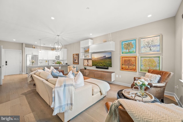 living room featuring light wood-type flooring and a notable chandelier