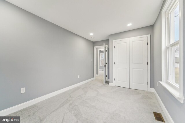 unfurnished bedroom with a closet and light carpet