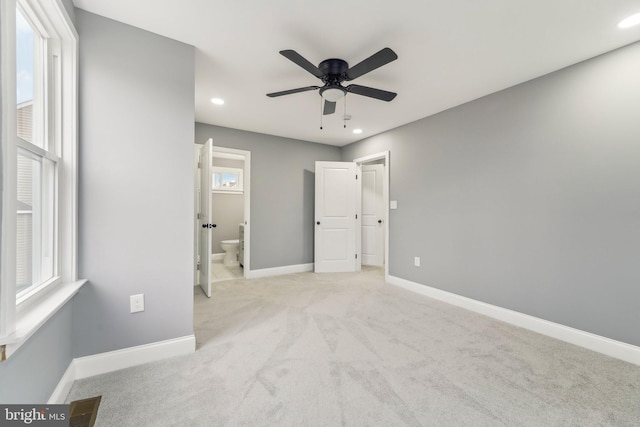 unfurnished bedroom with light colored carpet, ceiling fan, and ensuite bathroom