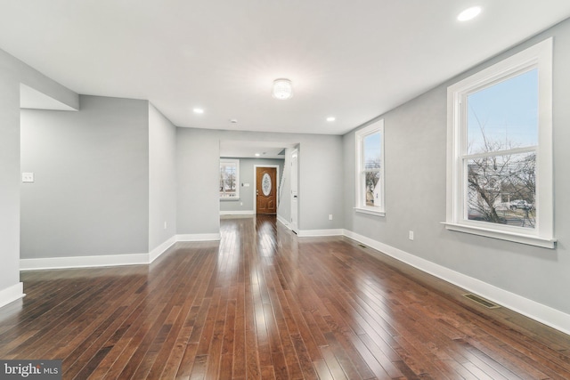 unfurnished living room featuring dark wood-type flooring and a wealth of natural light