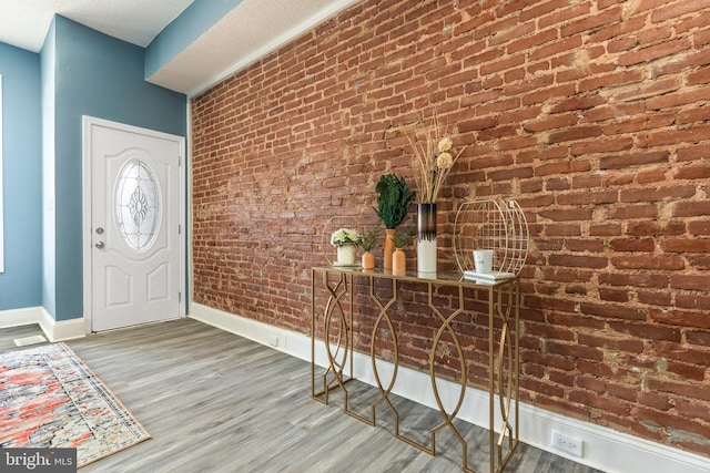 entrance foyer featuring brick wall and hardwood / wood-style floors