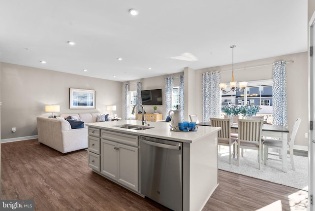 kitchen featuring pendant lighting, sink, dishwasher, dark hardwood / wood-style floors, and an island with sink