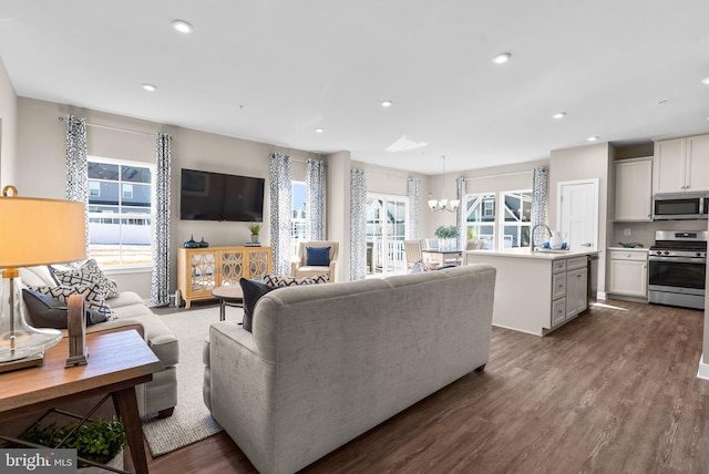 living room with an inviting chandelier, sink, and dark wood-type flooring