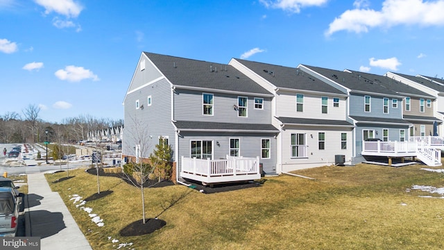 rear view of property with a wooden deck and a lawn